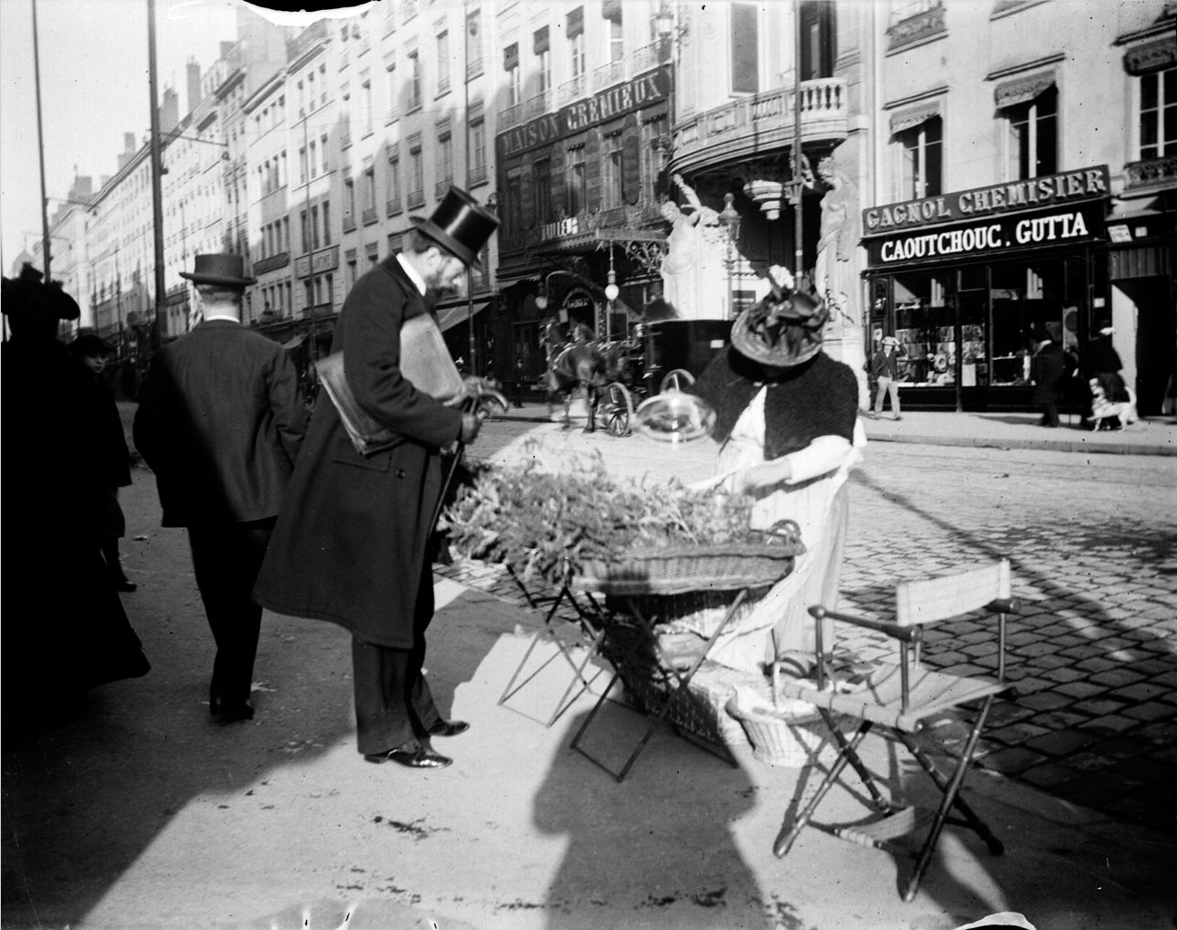 Marchande de plantes médicinales (?) à l'extrémité de la rue de la République : photo négative NB sur plaque de verre (vers 1900, cote : 10PH/152)