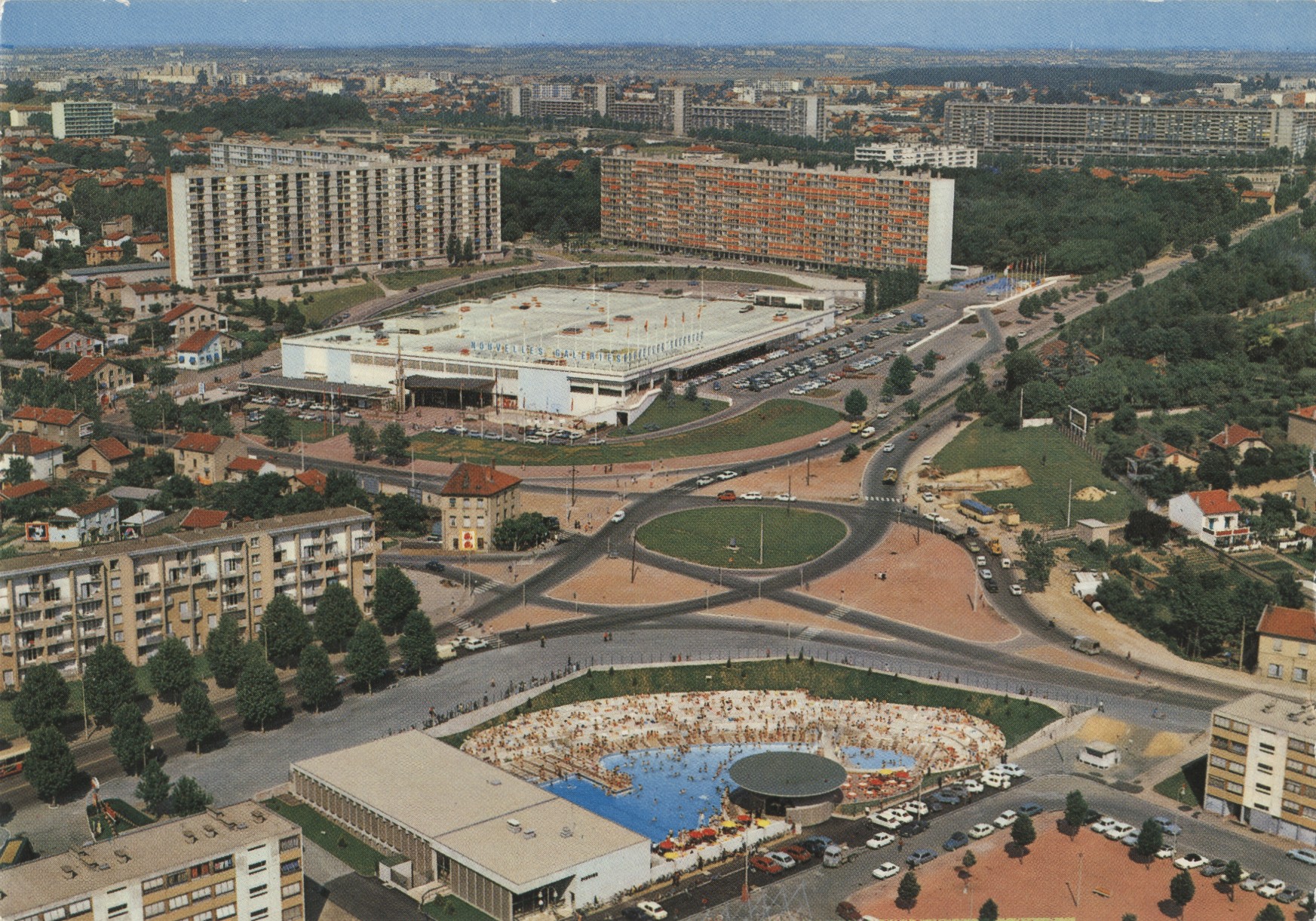Lyon - Au premier plan : piscine Mermoz , en second plan, les nouvelles galeries et Bron Parilly : carte postale couleur (vers 1960, cote : 4FI/5603, repro. commerciale interdite)