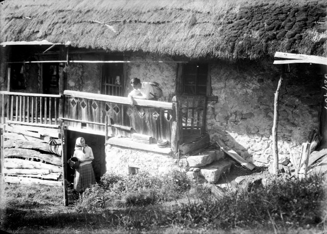 Ferme de l'Isère - Randonneur debout sur le balcon et paysanne sortant de la cave : épreuve photographique NB sur verre par Emile Poix ou Edmond Pernet (vers 1920, cote : 8PH/420)
