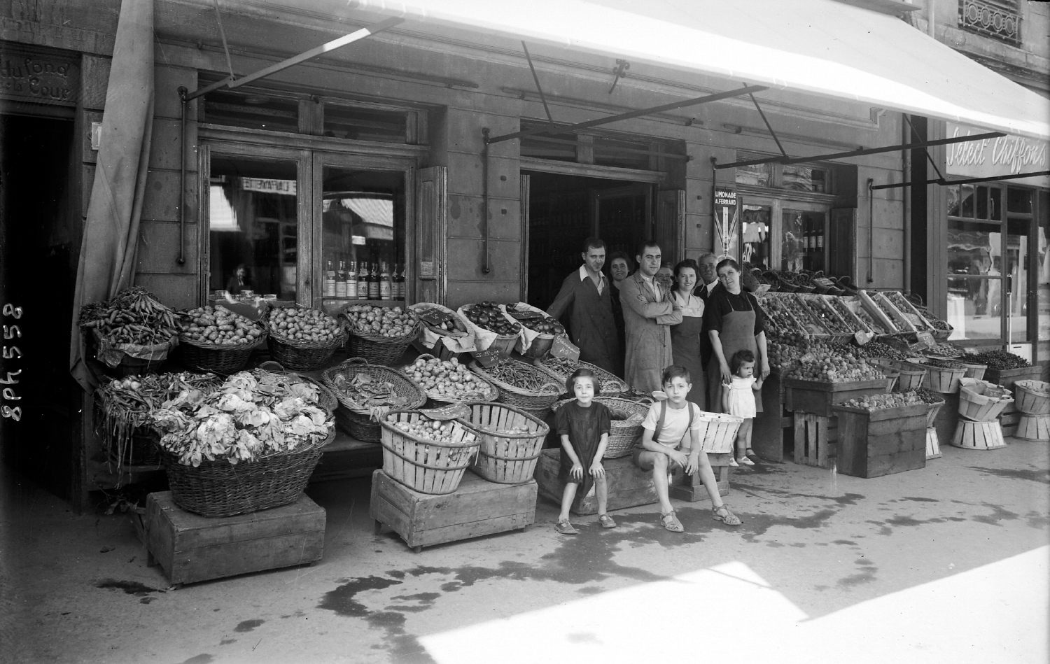 Commerce - épicier lyonnais et sa famille devant l'étalage de son épicerie : épreuve photographique NB sur verre par Emile Poix ou Edmond Pernet (vers 1930, cote : 8PH/558)