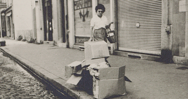 Photo d"'une dame marchant dans la rue à côté d'un tas de poubelles