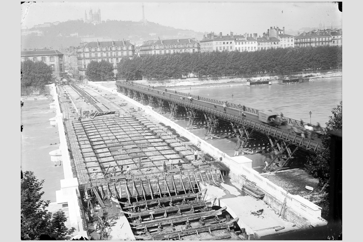 Photographie sur plaque de verre de la construction du Pont de l´Hôtel-Dieu sur le Rhône, v. 1916, fonds du service municipal de la voirie. On aperçoit la structure en béton armé du tablier et la passerelle provisoire en bois en amont du pont - 15PH/1/771