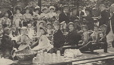 enfants mangeant sur des tables en extérieur vers 1910
