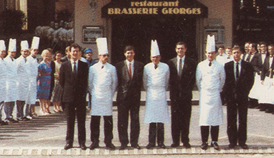 Des chefs en toque devant l'entrée de la Brasserie Georges