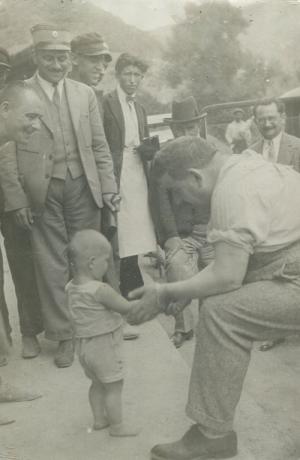 Edouard Herriot tenant la main d'un enfant au milieu d'un groupe d'hommes : tirage photo NB (s.d., fonds Louis Mandon, cote : 177II/2)