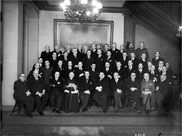 Groupe dans les salons de l'Hôtel de Ville en présence d'Edouard Herriot, maire de Lyon et du cardinal Gerlier, archevêque de Lyon : tirage photographique NB par E. Pernet ou E. Poix (vers 1930, cote : 8PH/8)