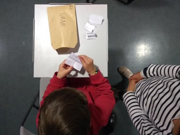 Photo d'enfants mettant un bulletin dans une enveloppe